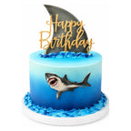 Great White Shark Cake featuring detailed shark figure and fin decoration with ocean-inspired blue frosting and gold "Happy Birthday" topper, perfect custom birthday cake.