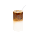 Iced latte with layered milk and coffee in a clear glass, topped with ice and a straw