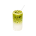 Iced matcha latte with milk in a clear glass, layered green and white, with straw