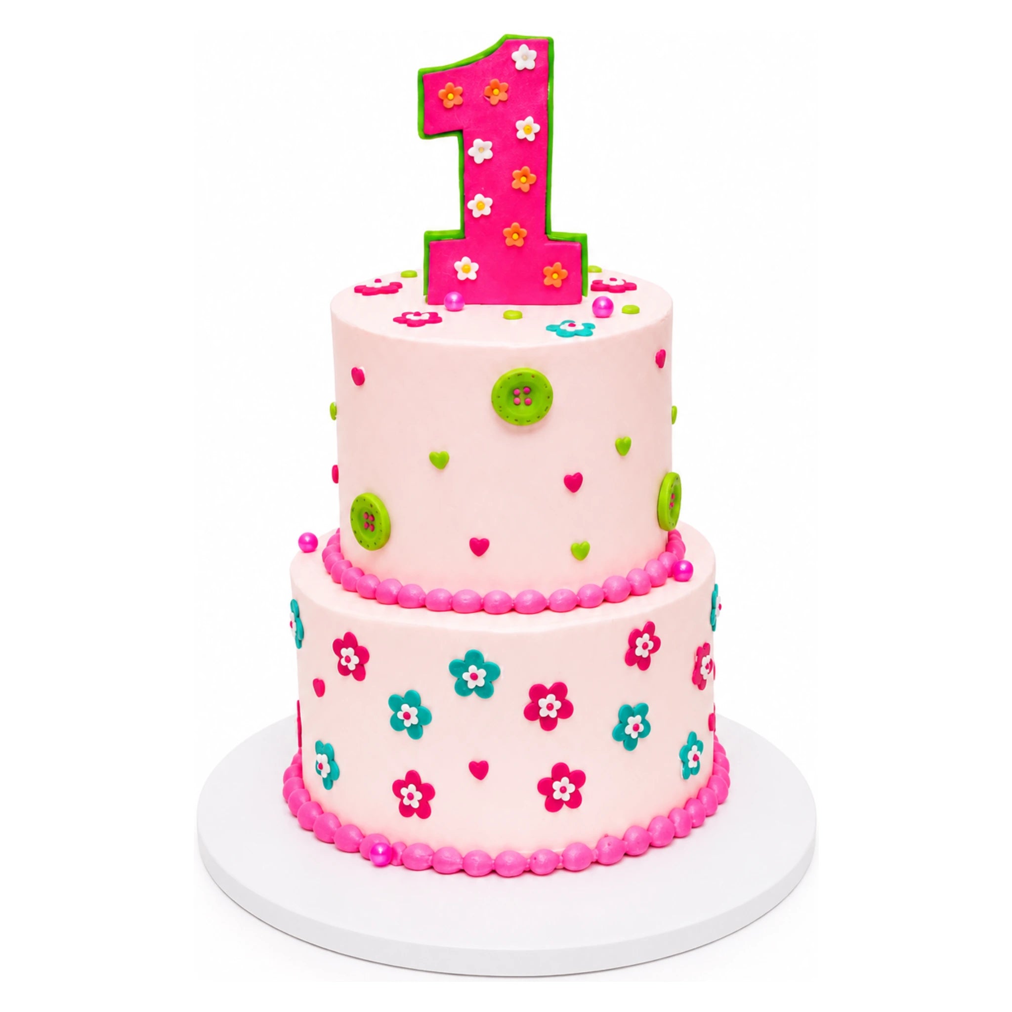 Two-tiered pink birthday cake decorated with colorful small flowers, green buttons, and tiny hearts, topped with a large pink number one outlined in green.