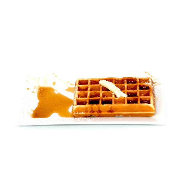 Golden Belgian waffle with syrup and butter on a white rectangular plate