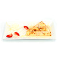 Tres leches crepes topped with cream, sliced strawberries, and whipped cream on a white plate