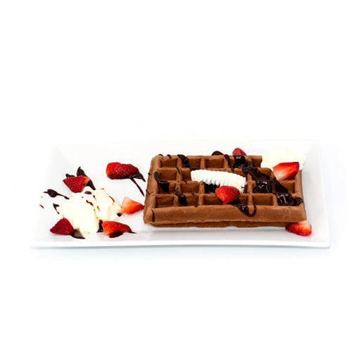 Chocolate waffle topped with banana, strawberries, whipped cream, and chocolate drizzles on white plate